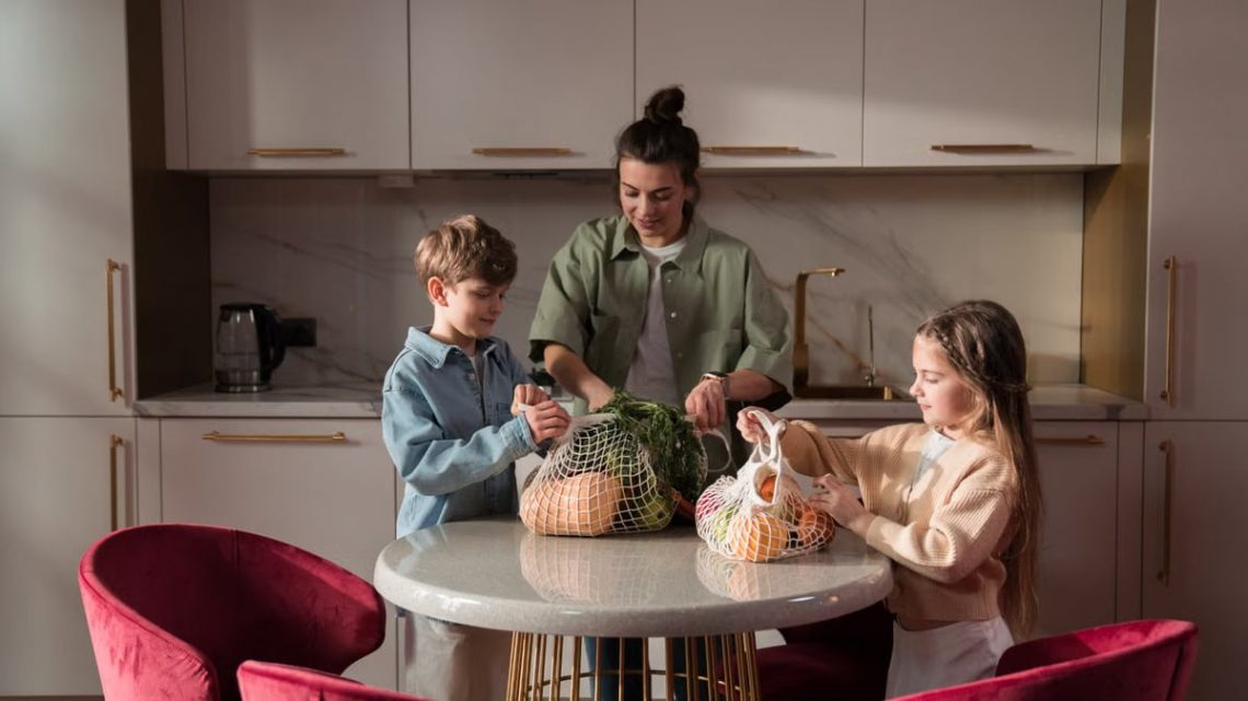 Mother and children unpack fresh vegetables in a modern kitchen, promoting family togetherness and a healthy lifestyle.