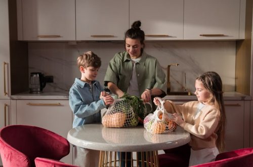 Mother and children unpack fresh vegetables in a modern kitchen, promoting family togetherness and a healthy lifestyle.