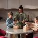 Mother and children unpack fresh vegetables in a modern kitchen, promoting family togetherness and a healthy lifestyle.